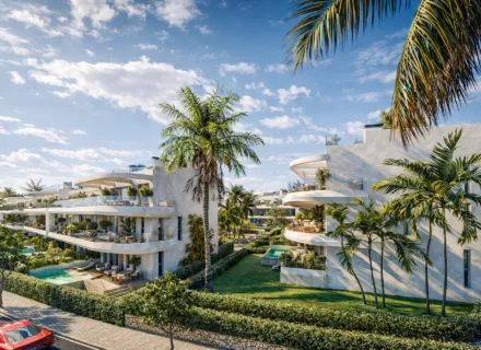 Luxury white apartment buildings with curved terraces, private pools, palm trees and landscaped gardens in Estepona, Spain.