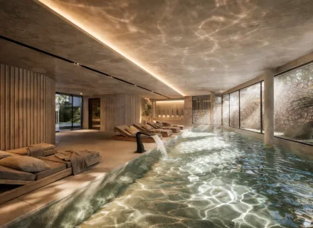 Elegant indoor spa area with heated pool, relaxation loungers, soft lighting and floor-to-ceiling windows in luxury residence.