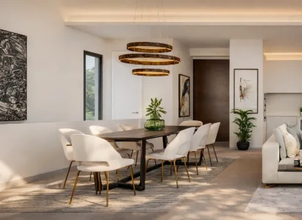 Modern dining area with long wooden table, white chairs, sculptural pendant lights, soft neutral palette and elegant open-plan interior