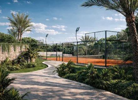 Tennis court at Sierra Blanca by the Sea surrounded by greenery and palm trees, exclusively for residents