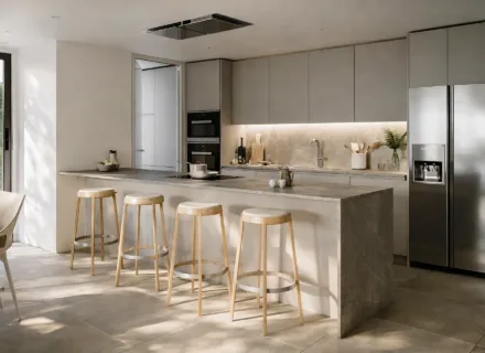 Modern kitchen at Ayana Estepona with elegant island, bar stools, built-in appliances and minimalist design in warm tones.
